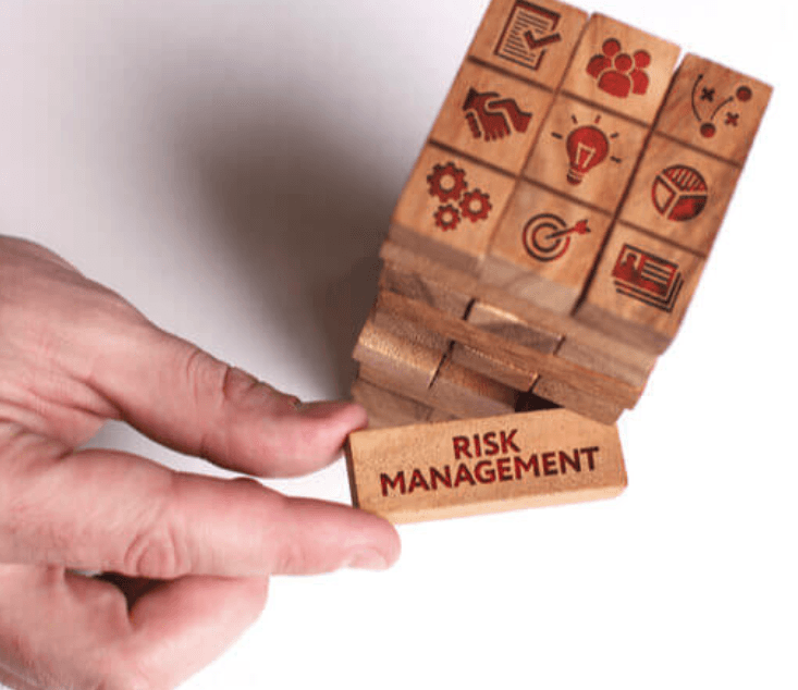 Jenga game with a hand pulling out a piece with "risk management" written on it